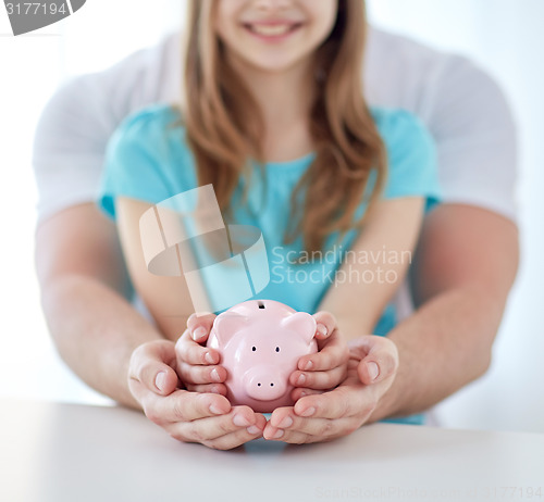 Image of close up of family hands with piggy bank