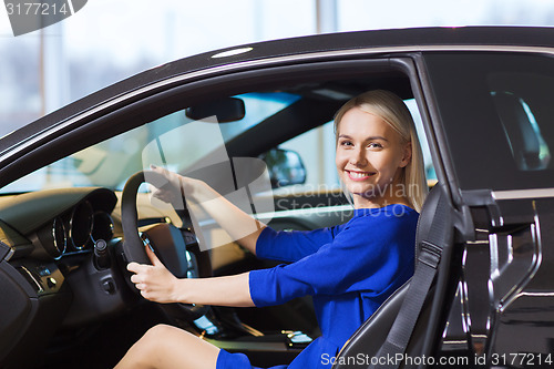 Image of happy woman inside car in auto show or salon