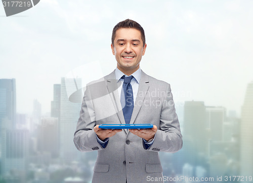 Image of happy businessman in suit holding tablet pc