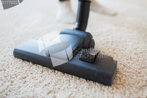 Image of close up of vacuum cleaner cleaning carpet at home