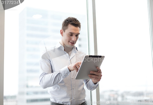 Image of smiling businessman with tablet pc in office