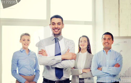 Image of smiling businessman in office with team on back