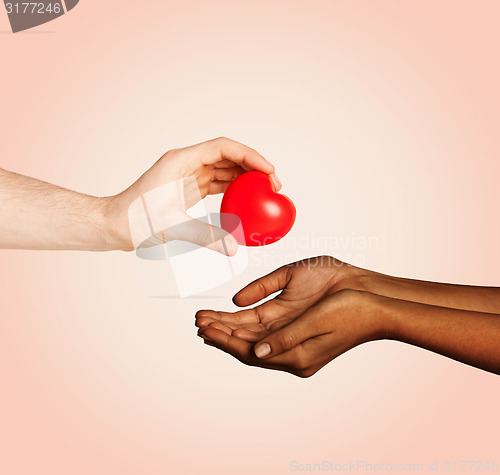 Image of woman and man hands with red heart