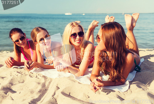 Image of group of smiling women in sunglasses on beach