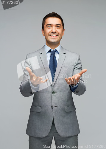 Image of happy businessman in suit showing empty palms