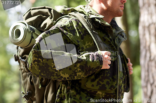 Image of close up of young soldier with backpack in forest