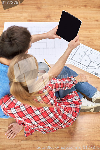 Image of close up of couple with tablet pc and blueprints