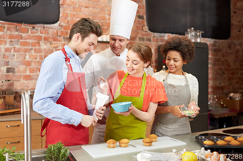 Image of happy friends and chef cook baking in kitchen