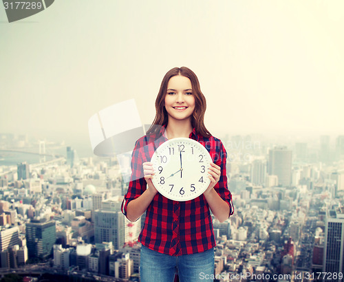 Image of young woman in casual clothes with wall clock