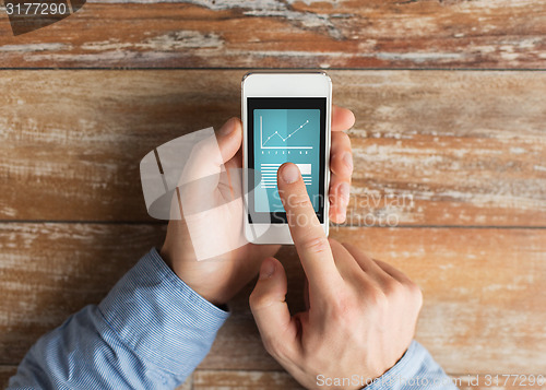 Image of close up of male hands with smartphone on table