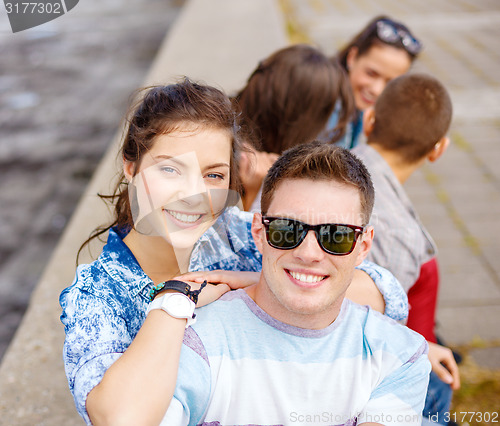 Image of smiling teenagers in sunglasses having fun outside