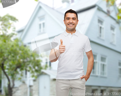 Image of man showing thumbs up over house background