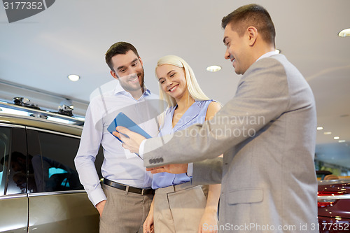 Image of happy couple with car dealer in auto show or salon