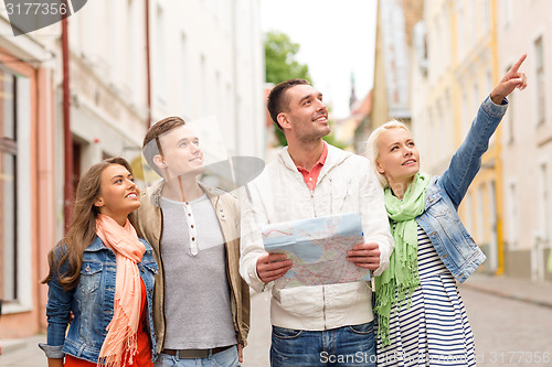 Image of group of smiling friends with map exploring city