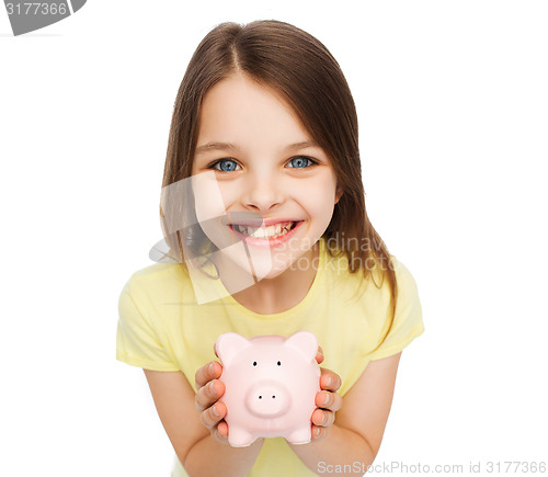 Image of beautiful little girl with piggy bank