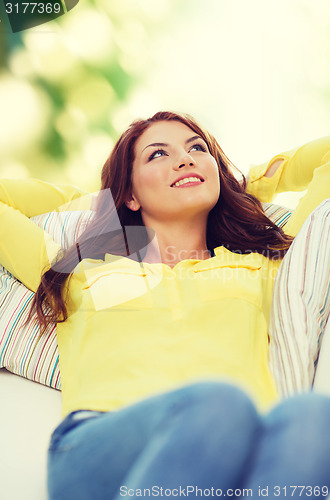 Image of smiling young woman lying on sofa at home