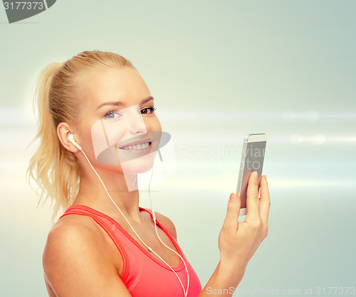 Image of smiling sporty woman with smartphone and earphones