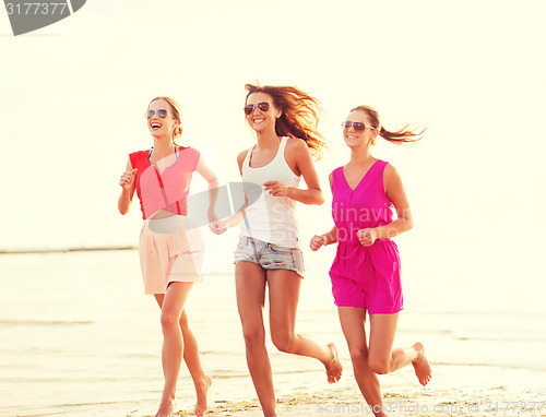 Image of group of smiling women running on beach