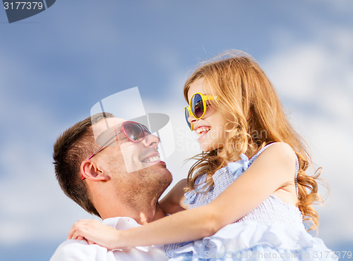 Image of happy father and child in sunglasses over blue sky