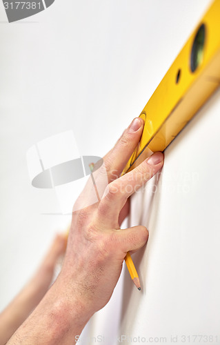 Image of close up of male hands with level measuring wall