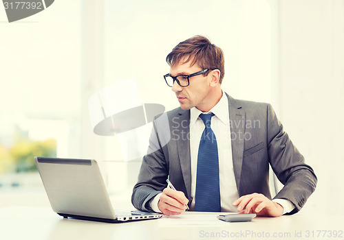 Image of businessman with computer, papers and calculator