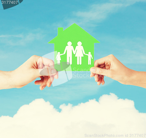 Image of hands holding green house with family