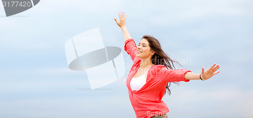 Image of girl with hands up on the beach