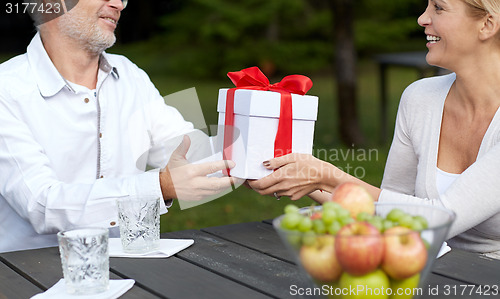 Image of happy family giving present in summer garden