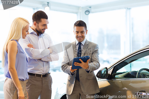 Image of happy couple with car dealer in auto show or salon