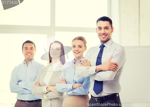 Image of smiling businessman in office with team on back