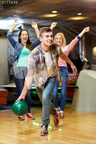 Image of happy young man throwing ball in bowling club
