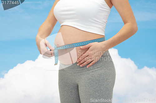 Image of close up of pregnant woman measuring her tummy