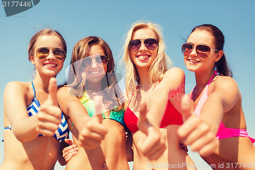 Image of group of smiling young women on beach