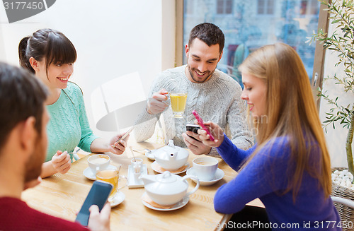 Image of group of friends with smartphones meeting at cafe
