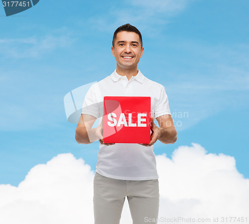 Image of smiling man with red sale sigh over blue sky