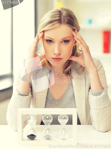 Image of pensive businesswoman with sand glass