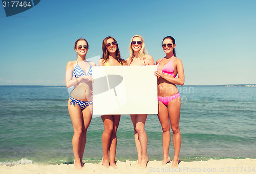 Image of group of smiling women with blank board on beach