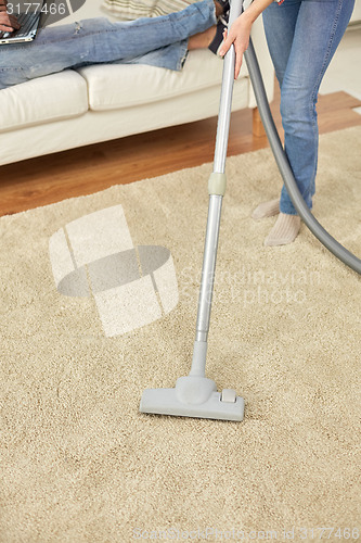 Image of close up of couple legs and vacuum cleaner at home