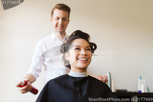 Image of happy woman with stylist making hairdo at salon