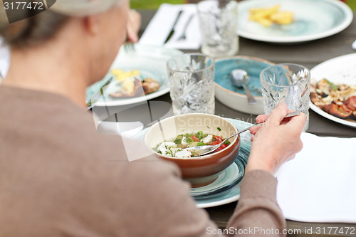 Image of close up of woman eating soup in summer garden