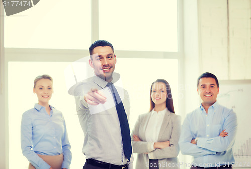 Image of businessman in office pointing finger at you