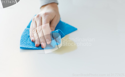 Image of close up of hand cleaning table surface with cloth
