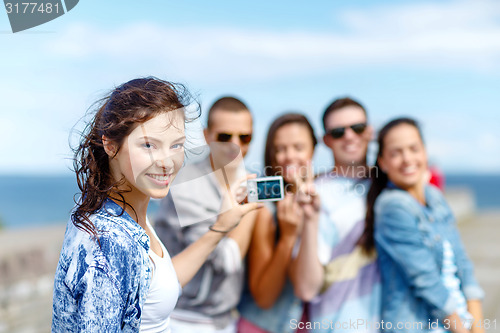 Image of happy teenagers taking photo outside