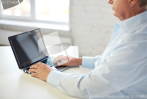 Image of close up of senior man with laptop typing