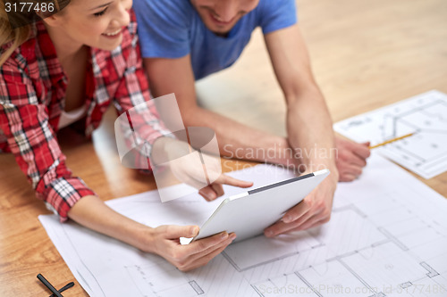 Image of close up of couple with tablet pc and blueprint