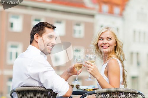 Image of smiling couple drinking wine in cafe