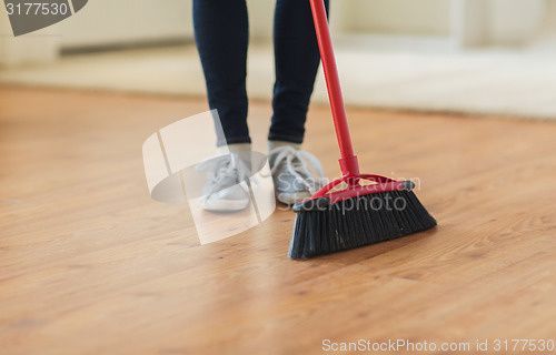 Image of close up of woman legs with broom sweeping floor