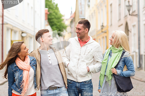 Image of group of smiling friends walking in the city