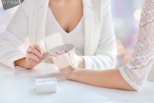 Image of close up of lesbian couple hands with wedding ring