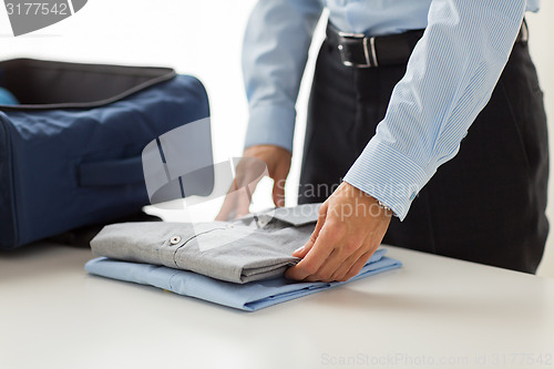 Image of businessman packing clothes into travel bag